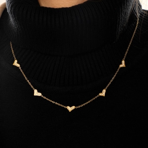 Detailed view of a gold plated necklace featuring five micro-pave heart shaped pendants