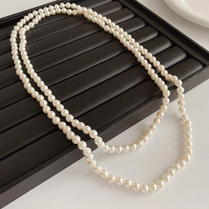 Detail of double-layer white pearl necklace on a black leather display tray