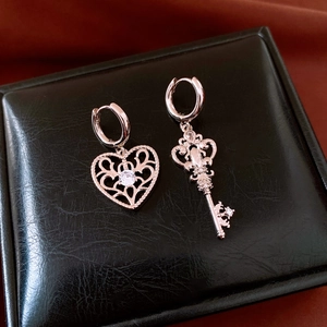 Detail view of asymmetric vintage heart and key earrings with sparkling zircon inlay