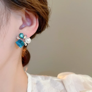 Close-up of floral crystal earrings with blue gemstones and pearls on model