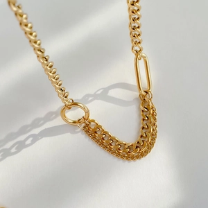 Detail of layered gold cuban chain necklace with chunky oval links and sleek metallic finish