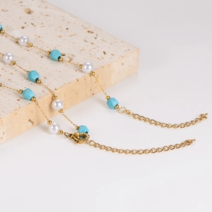 Collana dorata con perle e perline turchesi su una base in pietra naturale