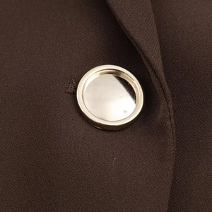 Detailed macro view of a metallic gold button on high-quality dark brown blazer fabric