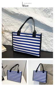 Detail of blue and white striped canvas tote bag with black strap and modern design