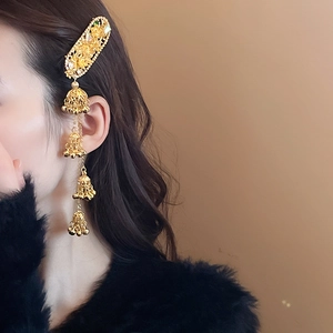 Detail of golden ethnic hair clip with floral engraving and dangling bell tassels