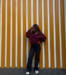 Photo en extérieur d'un sweat à col polo bordeaux foncé brodé avec un jean droit