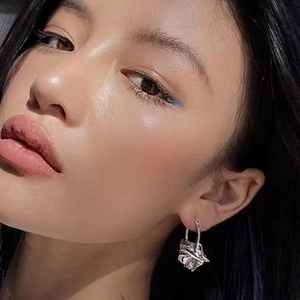Close-up of elegant silver rose-shaped hoop earrings featuring intricate hollow mesh texture