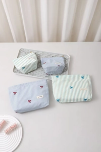 Detailed set of striped cosmetic bags with delicate bow embroidery and woven logo label