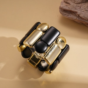 Detailed view of elastic bracelet with matte black and polished gold geometric modules