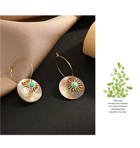 Detail of shell drop earrings with turquoise beads and sunburst design on satin