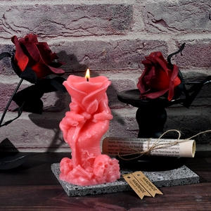 Close-up of a lit pink skeleton hand and rose candle with a Gothic romantic aesthetic