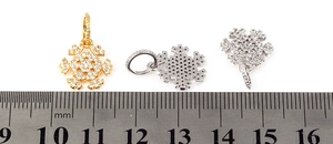 Detailed view of gold and silver snowflake pendants with zircon inlay shown against a ruler