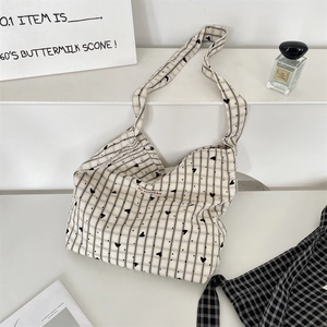Detail view of canvas hobo bag with black stripes, heart patterns and brand label