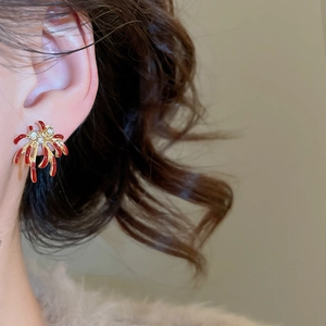 Gros plan d'une boucle d'oreille feu d'artifice en émail rouge et or avec zircon sur modèle