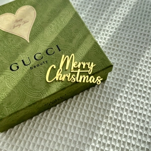 Close-up of golden mirror Merry Christmas acrylic cake topper on green gift box