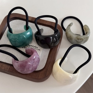 Set of five tortoiseshell hair ties in assorted colors on a wooden jewelry display tray
