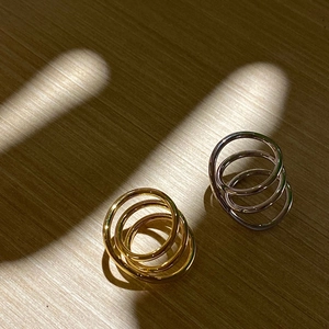 Detail of layered gold and silver rings with linear design on a wooden table