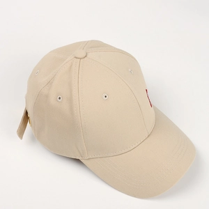 Detail einer beigen Baumwoll-Baseballkappe mit roter Stickerei und Metallösen