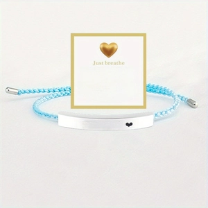 Macro shot of blue woven bracelet with engraved 'Just breathe' metal bar and gift card