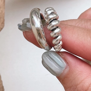 Macro shot of minimalist 925 sterling silver knotted and wide band rings on fingers