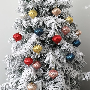 Colorful onion-shaped Christmas tree ornaments with glitter and ribbed textures on snowy branches