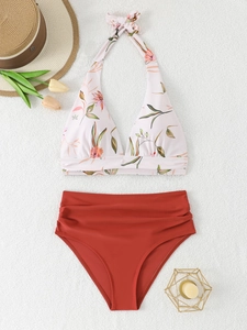 Detail of floral halter bikini top and high-waisted brick red bottoms on textured rug