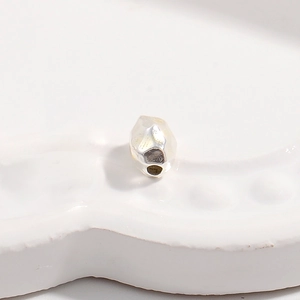 Macro shot of S925 sterling silver irregular faceted spacer bead on a white tray