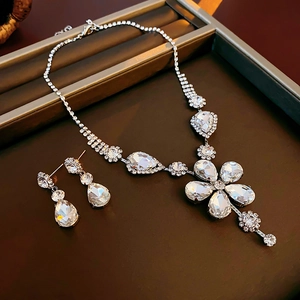 Macro view of silver floral necklace and drop earrings set with sparkling crystals