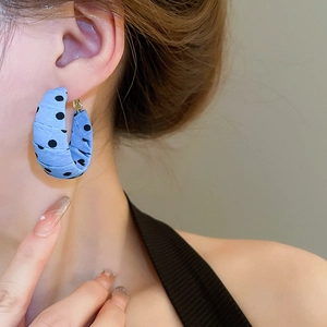 Detailed view of blue polka dot fabric wrapped hoop earring on model ear lobe