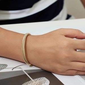 Close-up of golden cable wire open cuff bracelet styled on a male model wrist