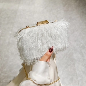 Detail of elegant white evening clutch featuring soft tassel texture and gold chain strap