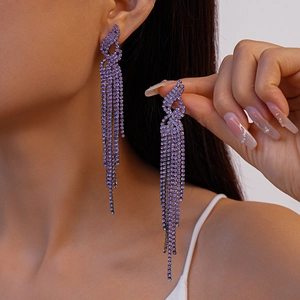 Elegant long purple tassel earrings with geometric crystal studs on a female model