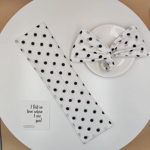 Detail of white black polka dot hair bun maker and bow scrunchie on a table