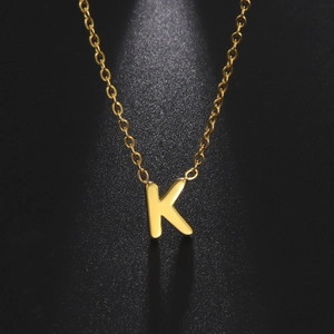Titanium steel gold necklace with letter K pendant against a black textured background