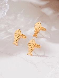 Detailed top view of three gold fishbone rings on white marble background with soft shadows