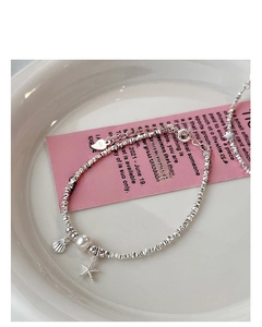 Detail of silver starfish bracelet with pearl shell charm and heart pendant