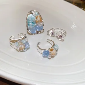 Coastal silver beaded rings with sea shells and blue stones on white ceramic plate
