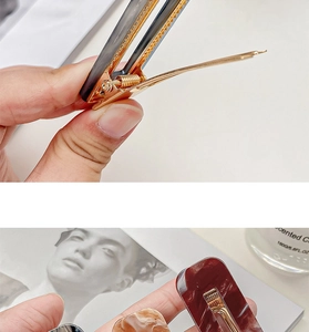 Detail view of wavy acrylic hair clips in dark and red tones with gold metal fasteners