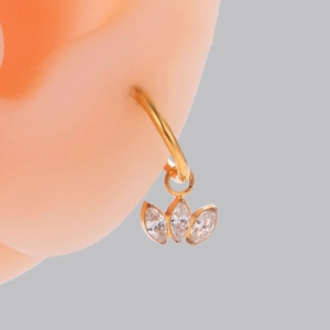 Close-up of gold hoop earrings with three marquise-cut zircon crystals on a model's ear