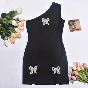Detail of rhinestone bow accents on a black one-shoulder mini dress with side slit