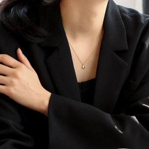 Minimalist gold oval pendant necklace for women worn on a black textured blazer