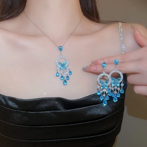 Macro detail of silver necklace set with blue water-drop gems and butterfly tassels