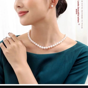 Close-up of elegant single-strand pearl necklace and matching stud earrings on a model