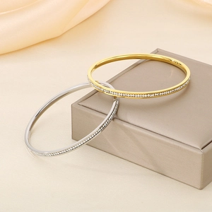 Luxury gold and silver titanium steel bracelets with pavé crystal accents on jewelry box