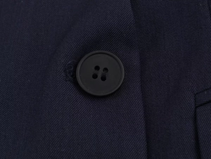 Macro shot of dark blue twill fabric texture and matte black four-hole buttons detail