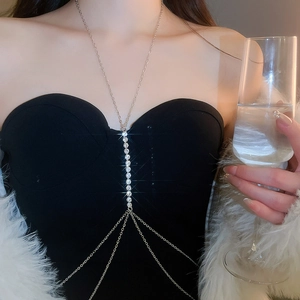 Detailed close-up of a sparkling crystal tassel chest chain on a model wearing black