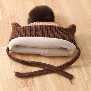 Detail of warm winter knit baby hat with plush pom-pom and soft cotton lining