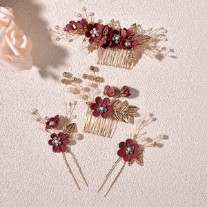 Detail of floral hair comb set with deep red fabric flowers and golden leaves