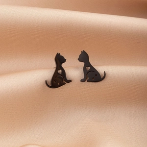 Close-up of black cat stud earring with heart and star cutouts on silk background