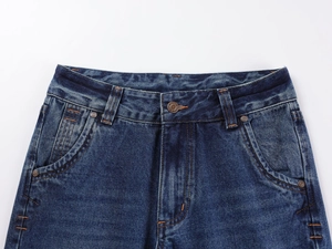 Detail of dark blue denim jeans showing heavy fabric texture and decorative metal button